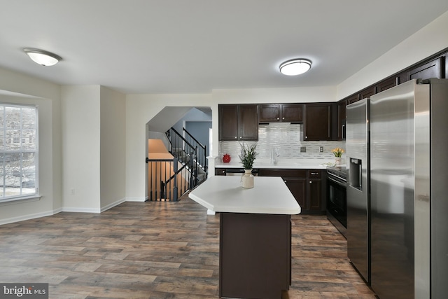 kitchen with a kitchen island, tasteful backsplash, dark hardwood / wood-style flooring, dark brown cabinetry, and stainless steel appliances