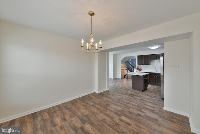 kitchen featuring an inviting chandelier, stainless steel refrigerator, dark hardwood / wood-style flooring, a kitchen island, and decorative backsplash