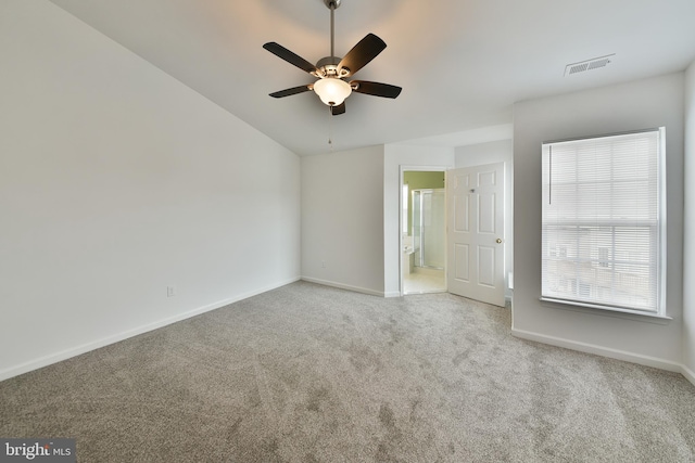 carpeted spare room featuring vaulted ceiling and ceiling fan