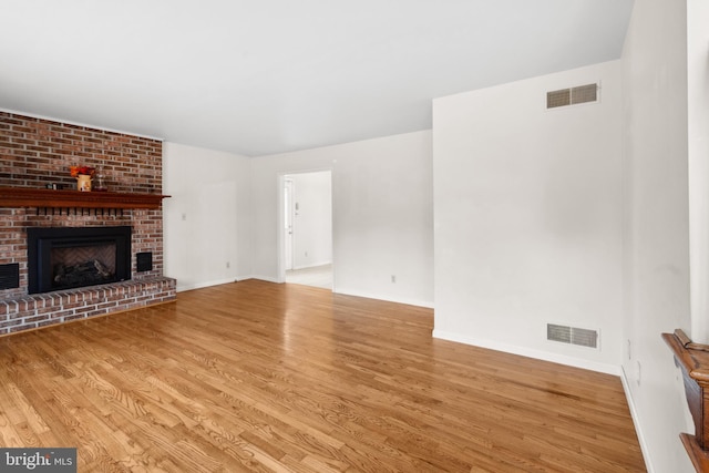 unfurnished living room featuring a fireplace, wood finished floors, visible vents, and baseboards