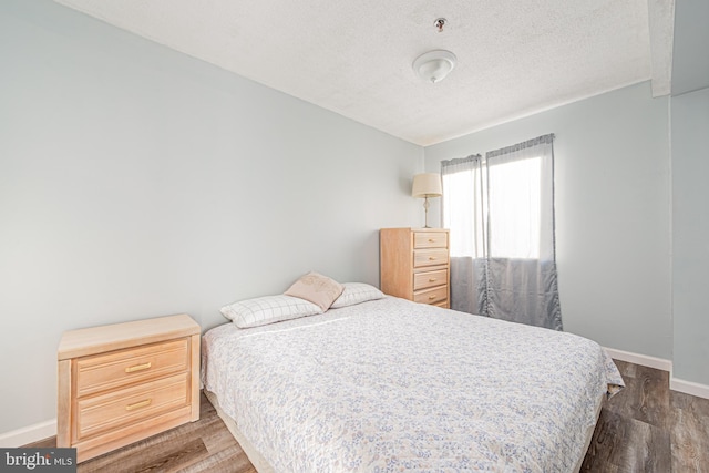 bedroom with dark hardwood / wood-style flooring and a textured ceiling