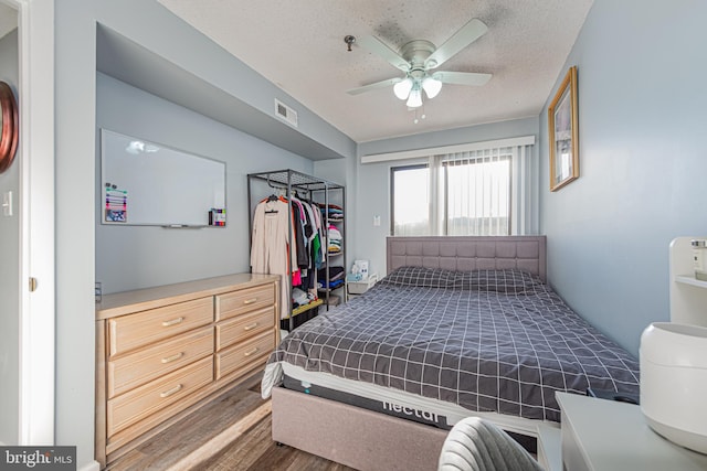 bedroom featuring ceiling fan, dark hardwood / wood-style floors, and a textured ceiling