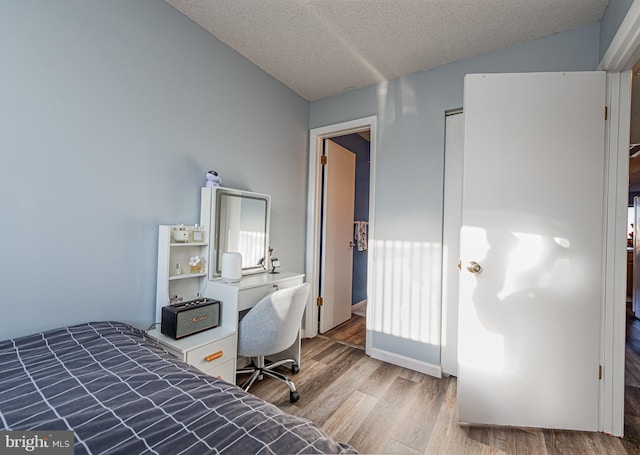 bedroom with lofted ceiling, wood-type flooring, and a textured ceiling