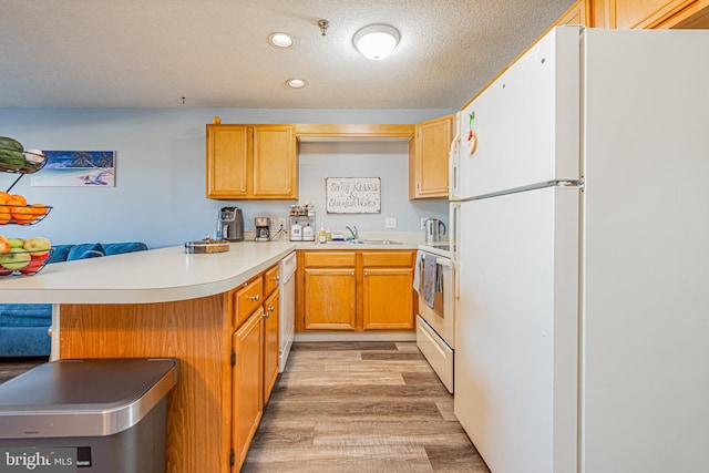 kitchen with a breakfast bar, sink, light hardwood / wood-style flooring, kitchen peninsula, and white appliances