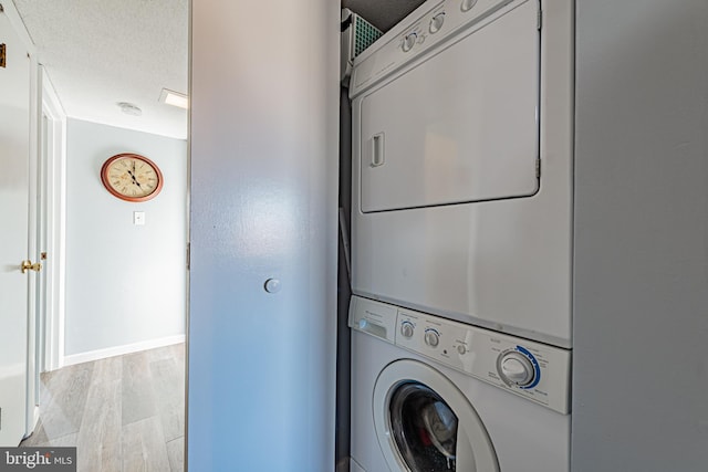 washroom with stacked washer and dryer, a textured ceiling, and light hardwood / wood-style flooring