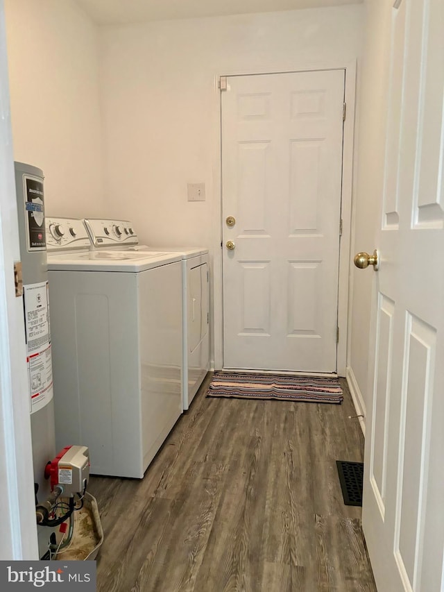 laundry room featuring gas water heater, dark hardwood / wood-style floors, and washing machine and clothes dryer