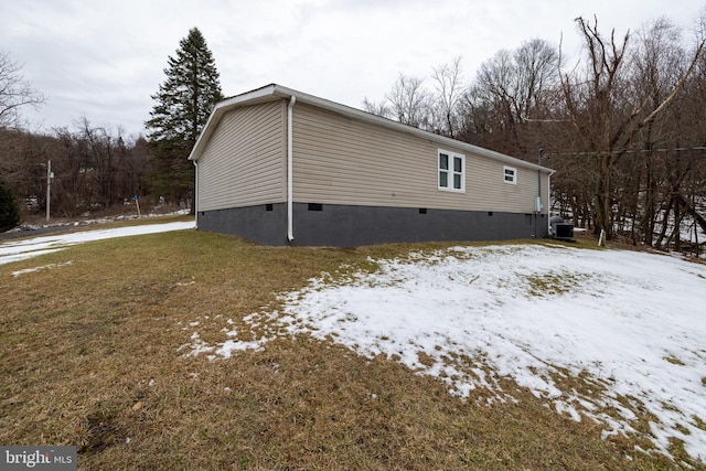 snow covered property featuring central AC unit and a lawn