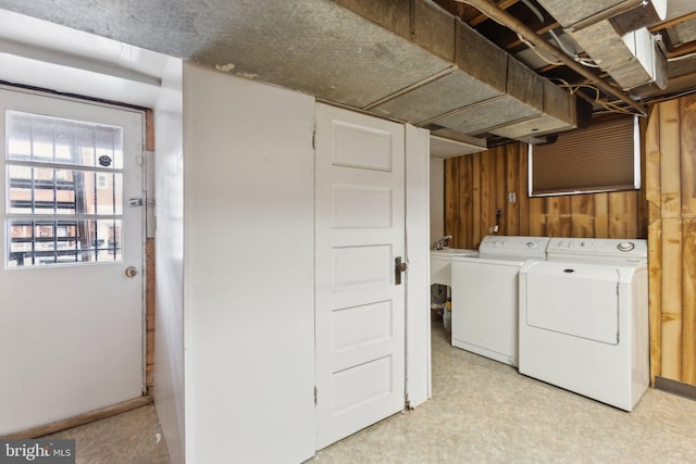 laundry room with washing machine and clothes dryer and wooden walls