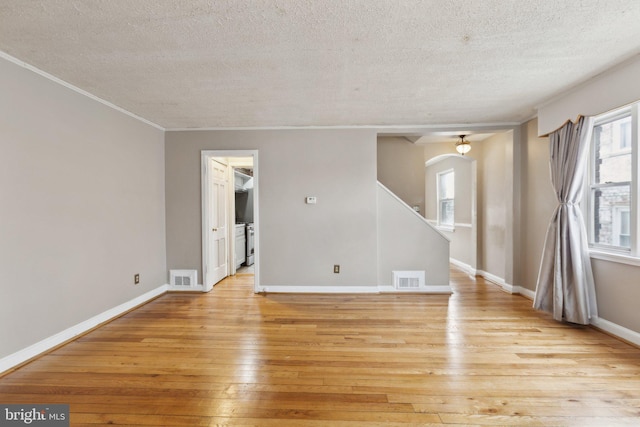 unfurnished room with washing machine and dryer, crown molding, a textured ceiling, and light hardwood / wood-style flooring