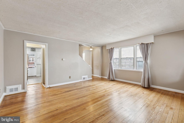 spare room with crown molding, light hardwood / wood-style flooring, and a textured ceiling