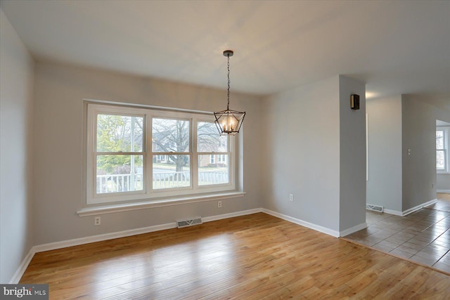 unfurnished dining area with an inviting chandelier and light hardwood / wood-style floors