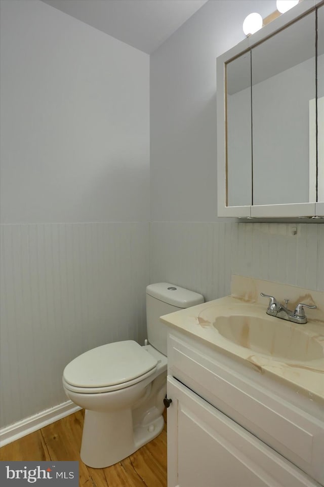 bathroom featuring wood-type flooring, toilet, and vanity