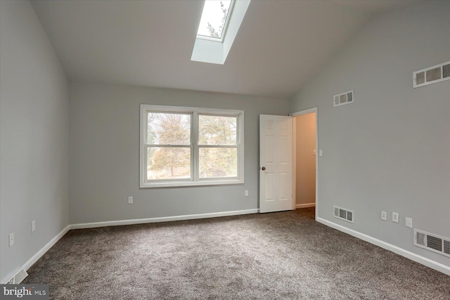 carpeted empty room featuring vaulted ceiling with skylight