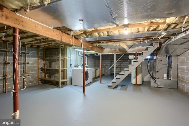 basement featuring water heater, washer and clothes dryer, and heating unit