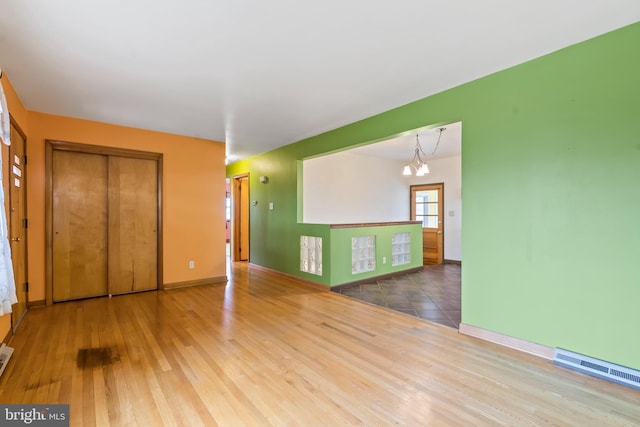 spare room with hardwood / wood-style flooring and an inviting chandelier