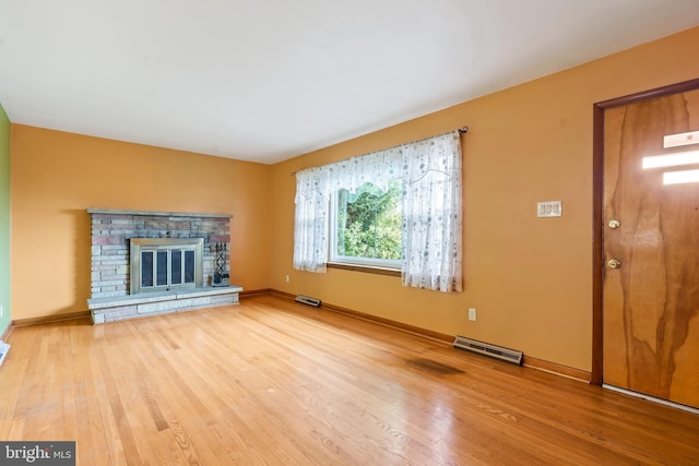 unfurnished living room with a stone fireplace and hardwood / wood-style flooring