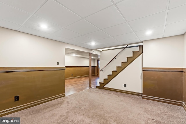 basement with a drop ceiling and light colored carpet