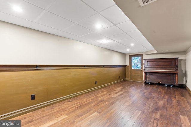 basement with a drop ceiling and dark hardwood / wood-style floors