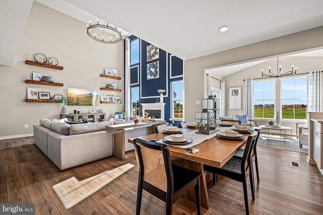 dining room with high vaulted ceiling, hardwood / wood-style floors, and a chandelier