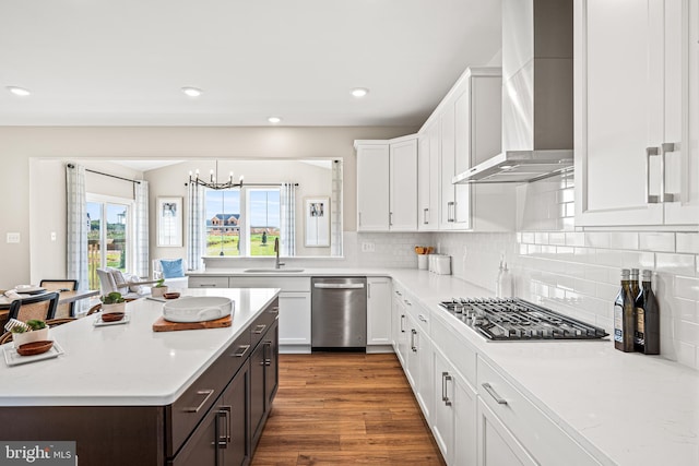 kitchen featuring sink, dark brown cabinets, wall chimney range hood, stainless steel appliances, and white cabinets