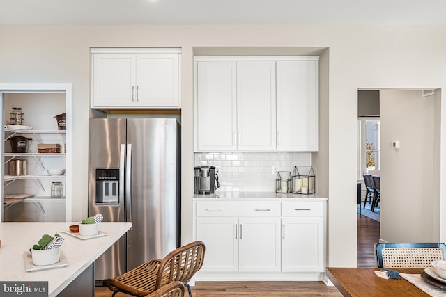 kitchen featuring white cabinetry, tasteful backsplash, stainless steel fridge with ice dispenser, and light hardwood / wood-style flooring