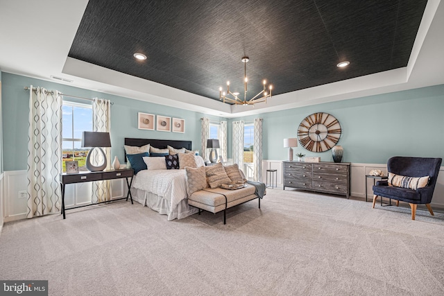 carpeted bedroom with a tray ceiling and a notable chandelier