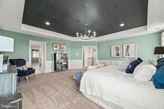 bedroom with a notable chandelier, a tray ceiling, and carpet