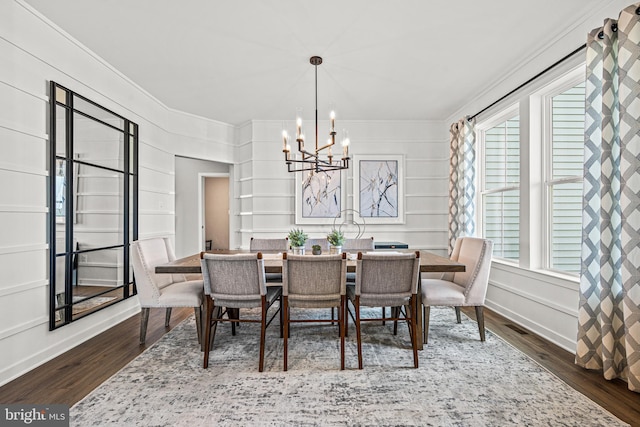 dining area with dark hardwood / wood-style flooring, ornamental molding, and a chandelier