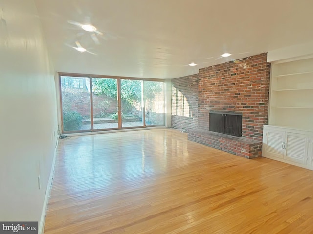 unfurnished living room featuring a fireplace, built in features, and light wood-type flooring