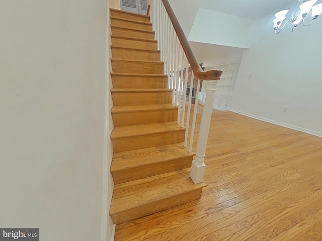 stairs with hardwood / wood-style floors and a chandelier