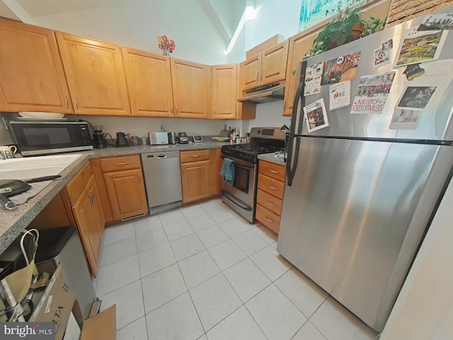 kitchen featuring lofted ceiling, light tile patterned floors, and stainless steel appliances