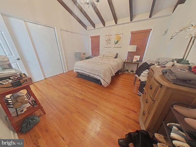 bedroom with hardwood / wood-style flooring, multiple closets, and vaulted ceiling with beams