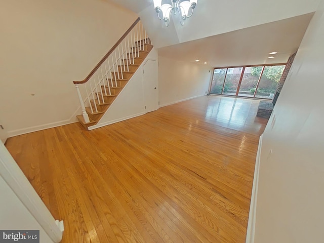 unfurnished living room with a notable chandelier and light hardwood / wood-style flooring