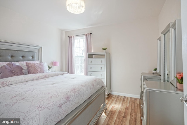 bedroom with light hardwood / wood-style flooring and a notable chandelier