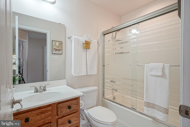 full bathroom with enclosed tub / shower combo, vanity, and toilet