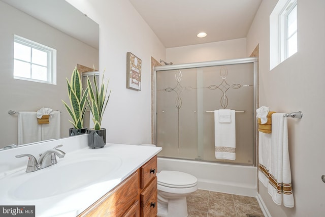 full bathroom featuring tile patterned flooring, bath / shower combo with glass door, vanity, and toilet