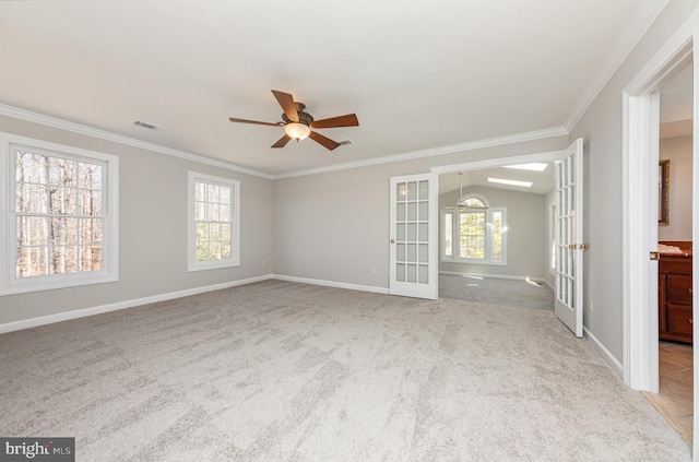 empty room with carpet floors, a healthy amount of sunlight, crown molding, and french doors