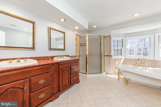 full bath with a stall shower, double vanity, a sink, and tile patterned floors