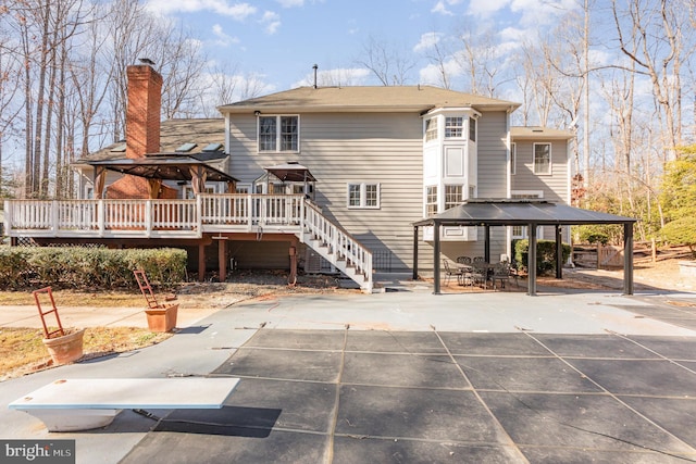 rear view of property featuring a deck, a gazebo, a patio, and stairs