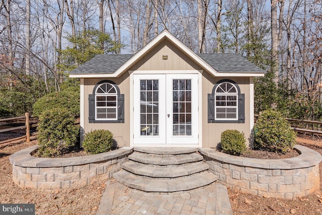 view of outbuilding with french doors, an outdoor structure, and fence