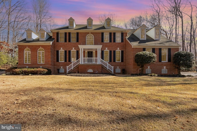 georgian-style home featuring brick siding and a front lawn