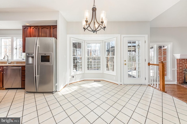 kitchen featuring hanging light fixtures, stainless steel appliances, a sink, and light tile patterned flooring