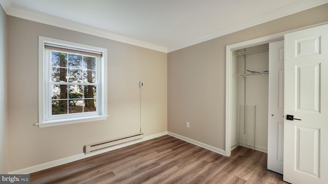 unfurnished bedroom featuring crown molding, wood-type flooring, a closet, and a baseboard heating unit