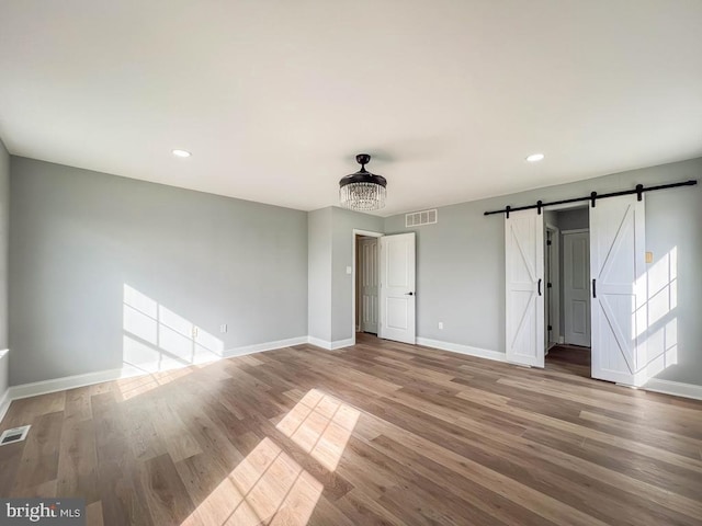 unfurnished bedroom featuring wood-type flooring and a barn door