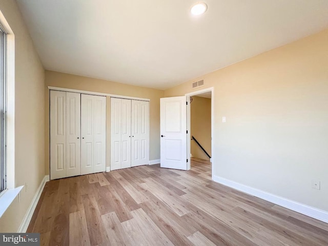 unfurnished bedroom with multiple closets and light hardwood / wood-style flooring