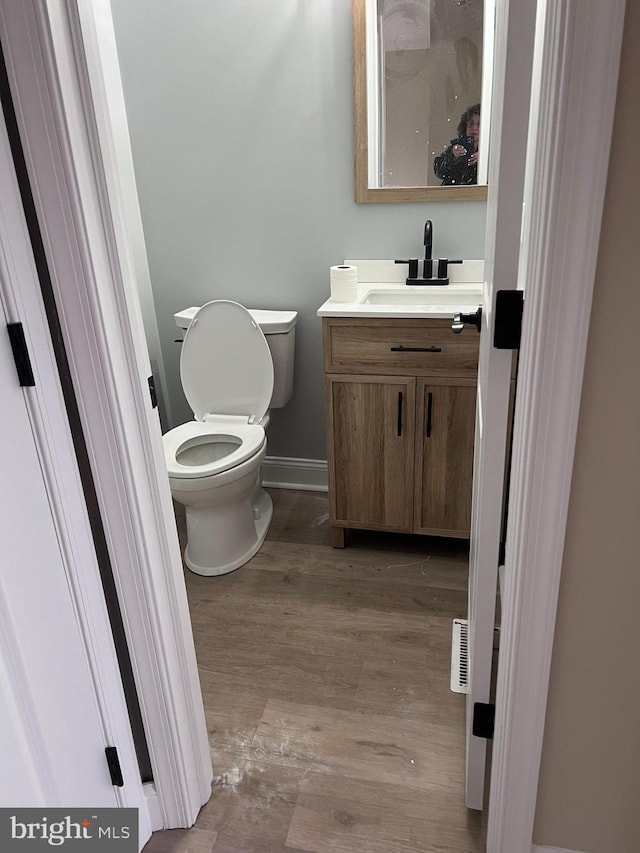 bathroom with vanity, hardwood / wood-style flooring, and toilet