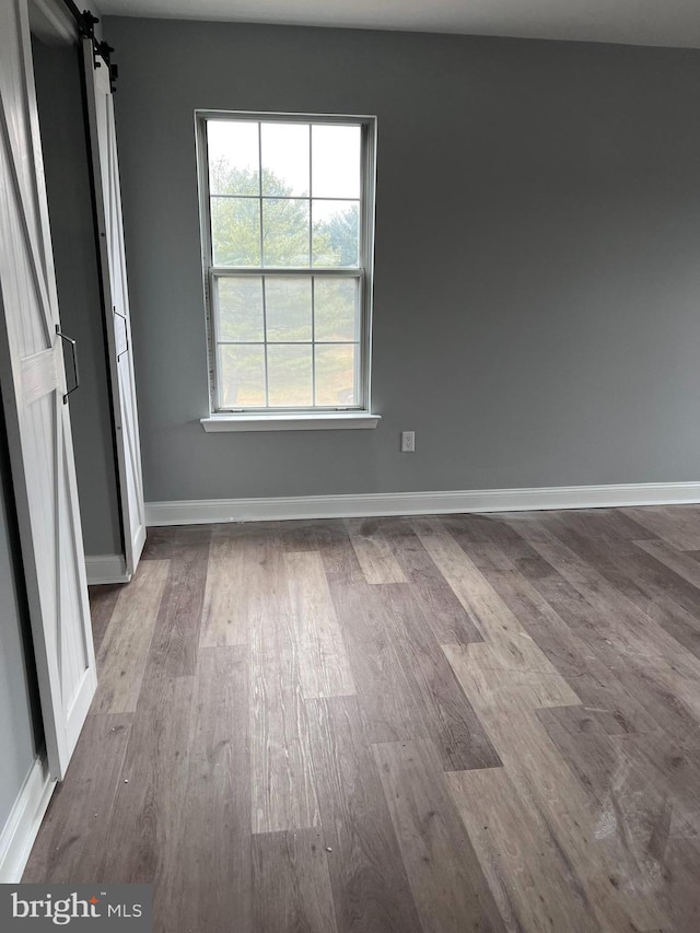 spare room featuring a barn door and light hardwood / wood-style floors