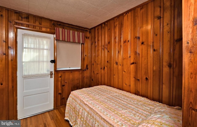 bedroom featuring wooden walls and light hardwood / wood-style floors