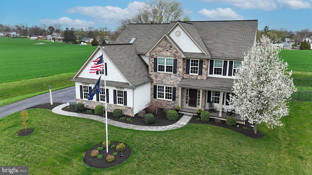 view of front of property with stone siding, a porch, a front lawn, and stucco siding