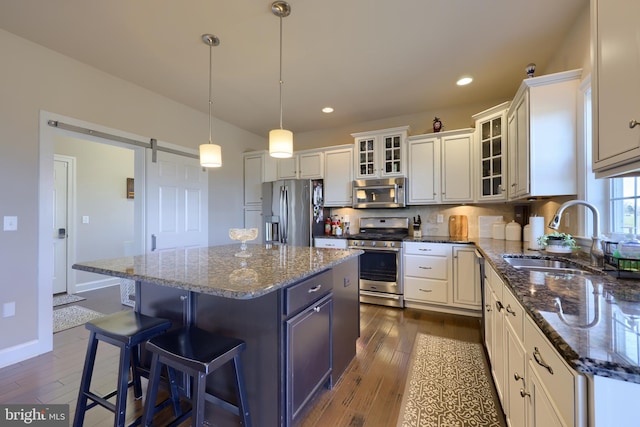 kitchen with a sink, a breakfast bar area, stainless steel appliances, dark wood-type flooring, and a kitchen island